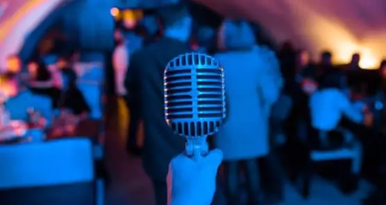 Microphone is on stage in a nightclub. Singer holds and sings into the microphone. Bright light of the club Shine on the MIC. Performances in the nightclub